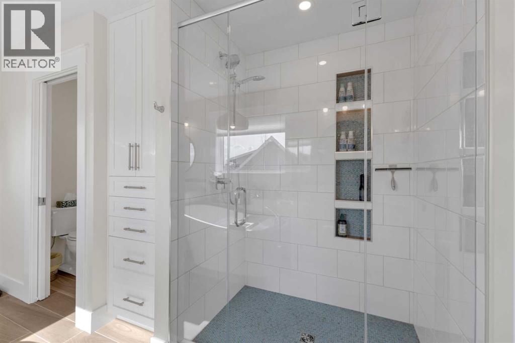 Tiled, walk-in shower with glass enclosure and built-in storage niche