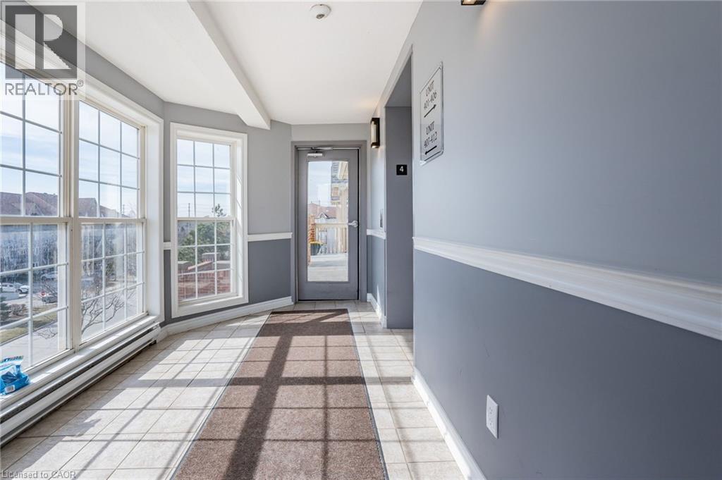 Light-filled hallway featuring multiple grid-paned windows, a paneled glass entry door, and large format tile flooring