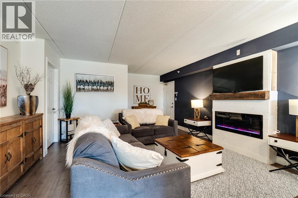 Living area featuring an electric fireplace with a wood mantle, an accent wall, and wood-finish flooring