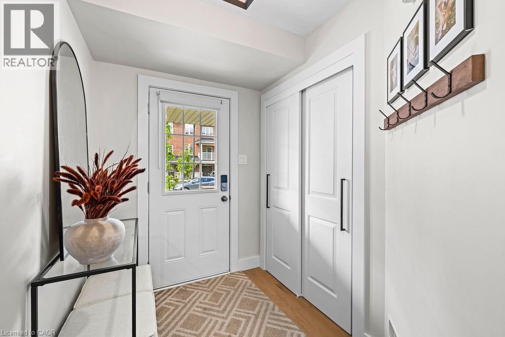 Entryway featuring a white paneled door with windowpanes, light wood-finish flooring, and white sliding closet doors with black hardware