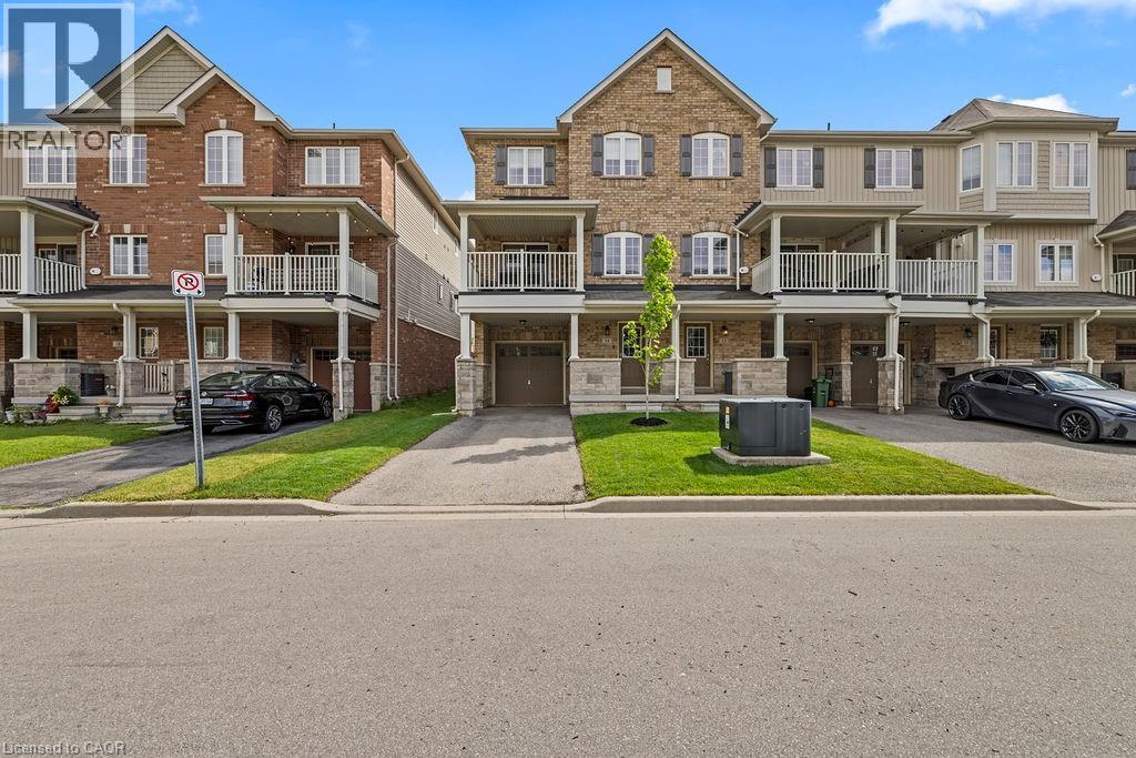 Three-story townhome featuring a brick and siding exterior, private driveway, and an integrated garage