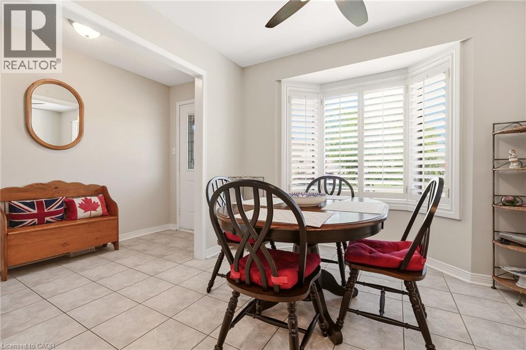 Dining area featuring a bay window with plantation shutters, tile flooring, and a ceiling fan