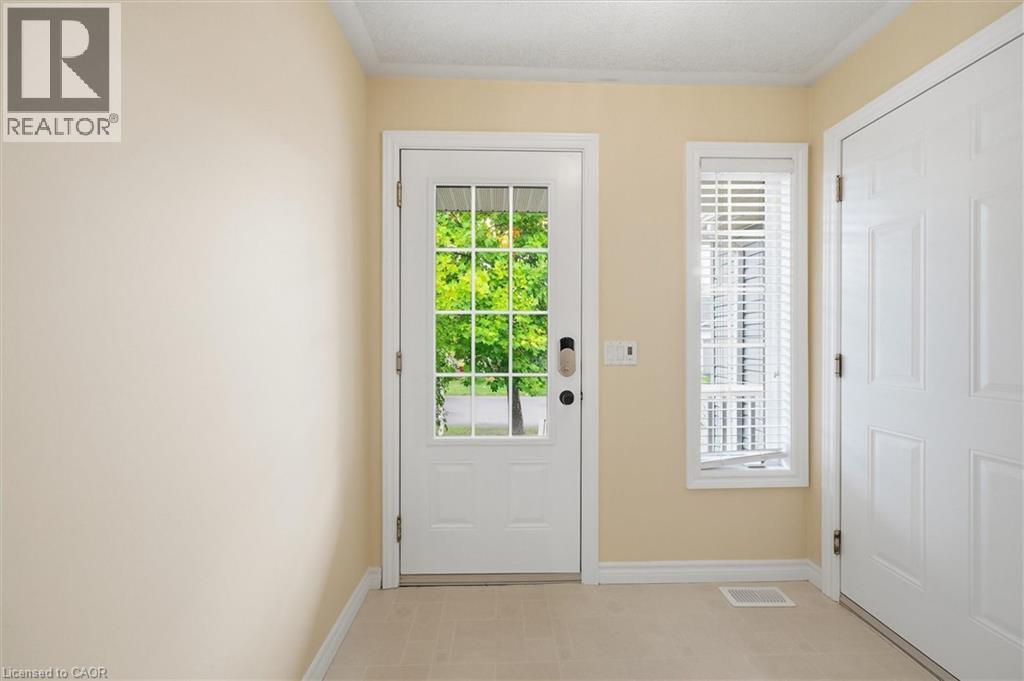 Entryway featuring a white paneled door with glass inserts, a vertical window with blinds, light beige walls, and light-colored tile flooring