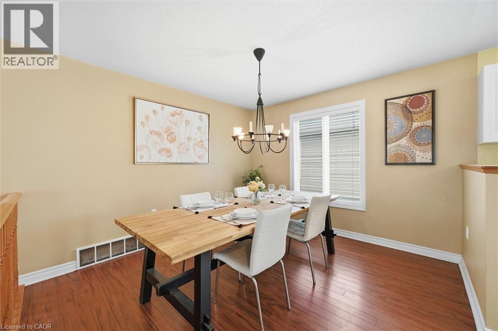 Dining area featuring wood-finish flooring, a contemporary chandelier, and a window with blinds