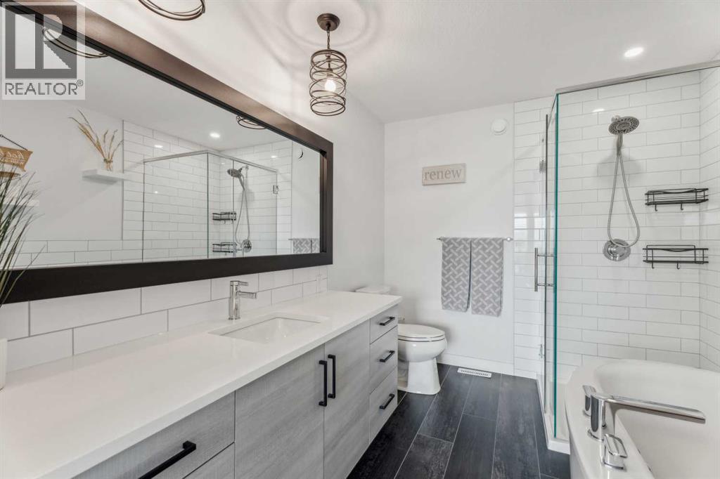Primary bathroom featuring a soaker tub, glass shower, and stylish quartz finishes