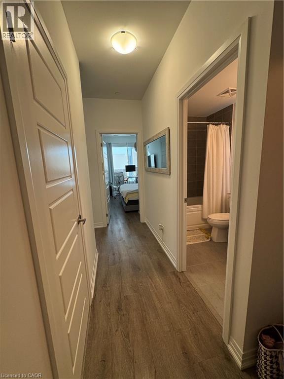 Hallway with wood-finish flooring, white baseboards, and a flush-mount ceiling light fixture