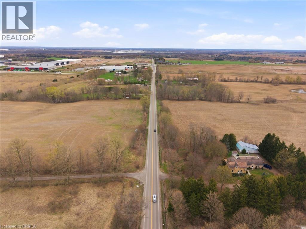 Expansive rural landscape featuring a long road, surrounding fields, and scattered trees