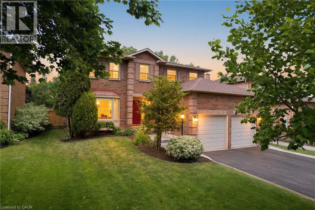 Brick facade residence featuring a two-car garage, a paved driveway, and a manicured lawn
