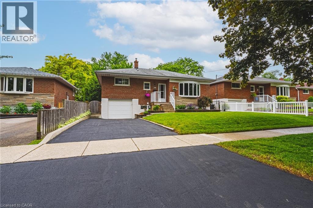 Brick exterior with stone accents, bay windows, white railings, attached garage, and paved driveway