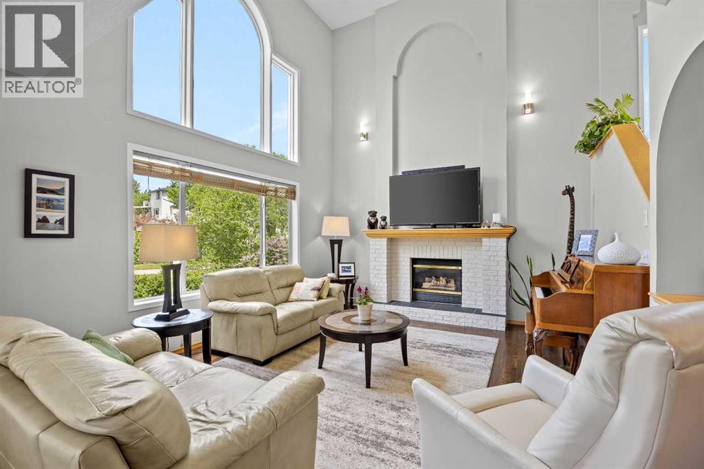 Dramatic arched windows flood the space with natural light, while the fireplace anchors a warm, elegant gathering space