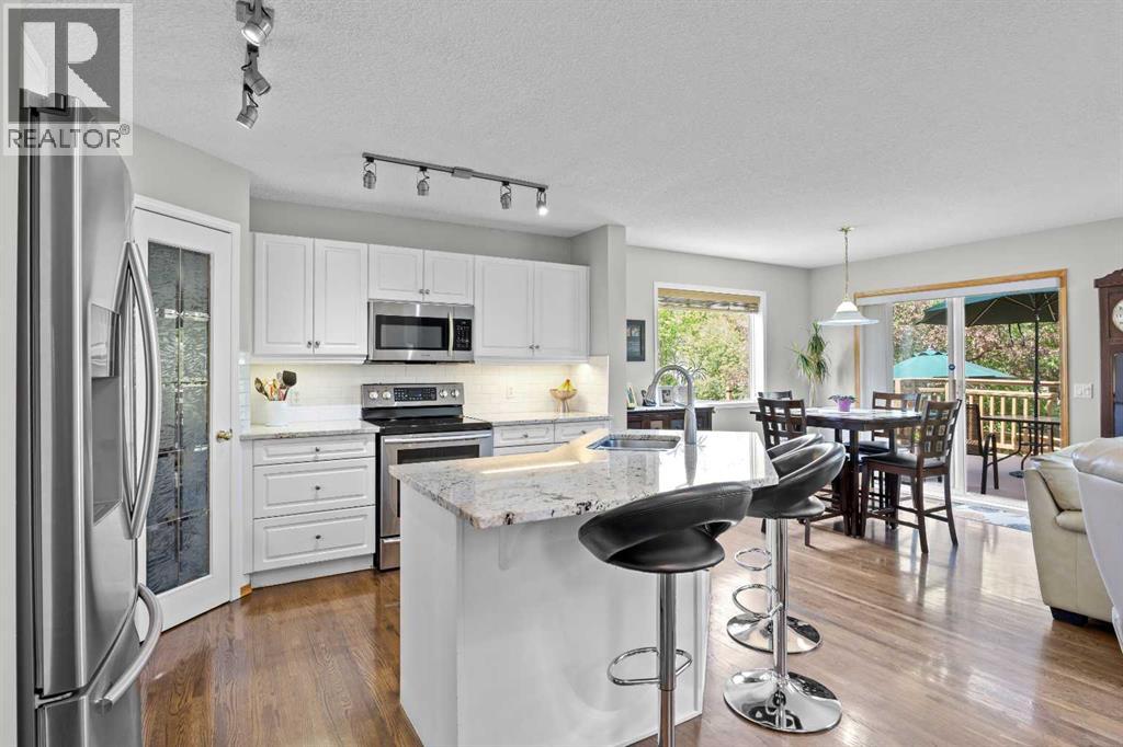 A bright, open kitchen with granite counters and stainless steel appliances flows effortlessly into the sunny eating area and out to the deck