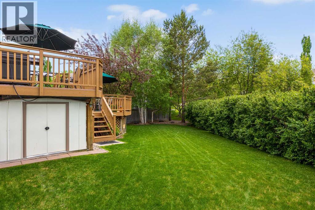 Lush lawn, mature hedging for privacy, and a handy storage shed tucked neatly beneath the deck