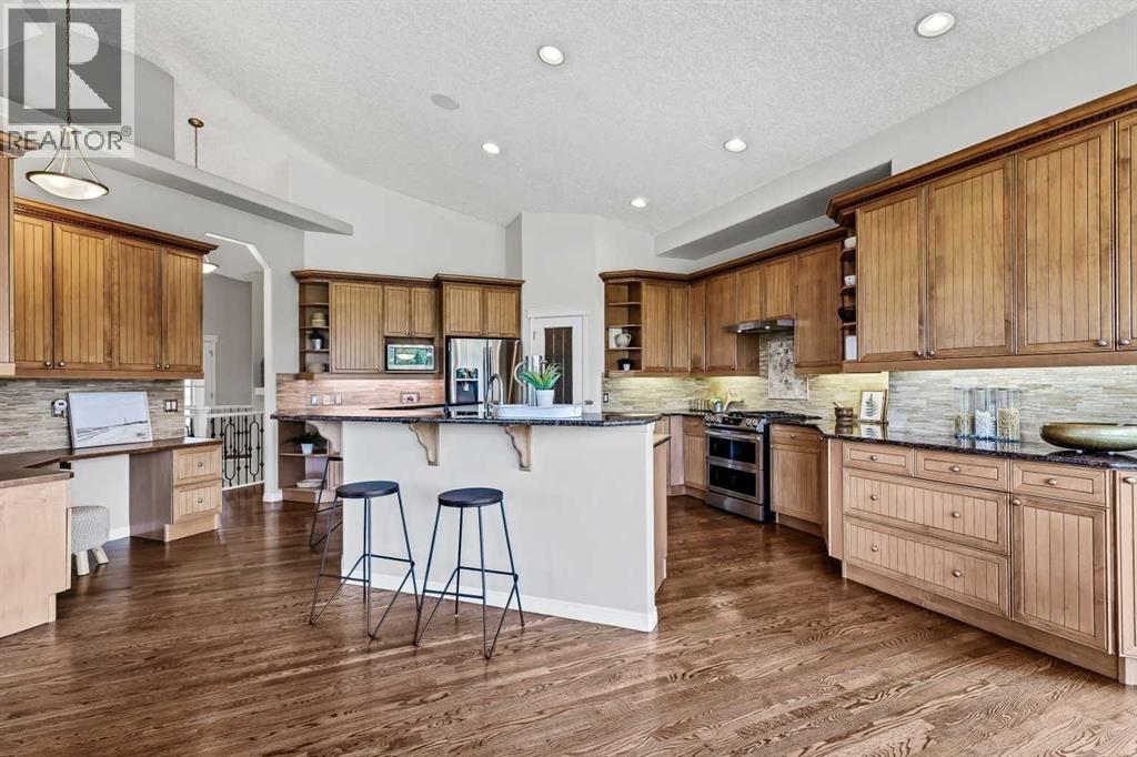 Gourmet kitchen boasts custom cabinetry, granite countertops, a granite double sink, and upgraded backsplash
