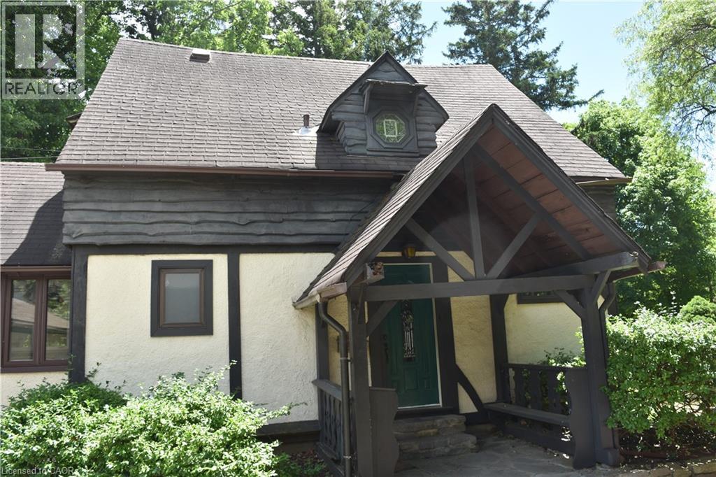 Tudor Revival-style exterior featuring decorative half-timbering, stucco finish, a covered entry porch with exposed wood beams, and a prominent dormer with an ornate window