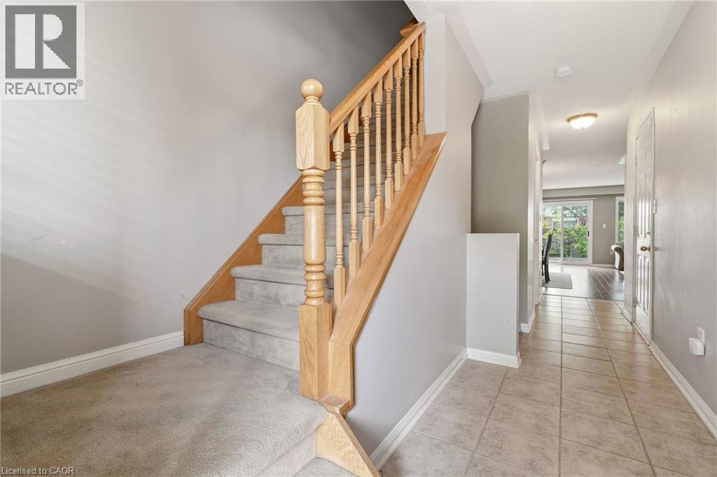 Foyer featuring light-toned tile flooring, a carpeted staircase with wood handrail, and a white paneled interior door