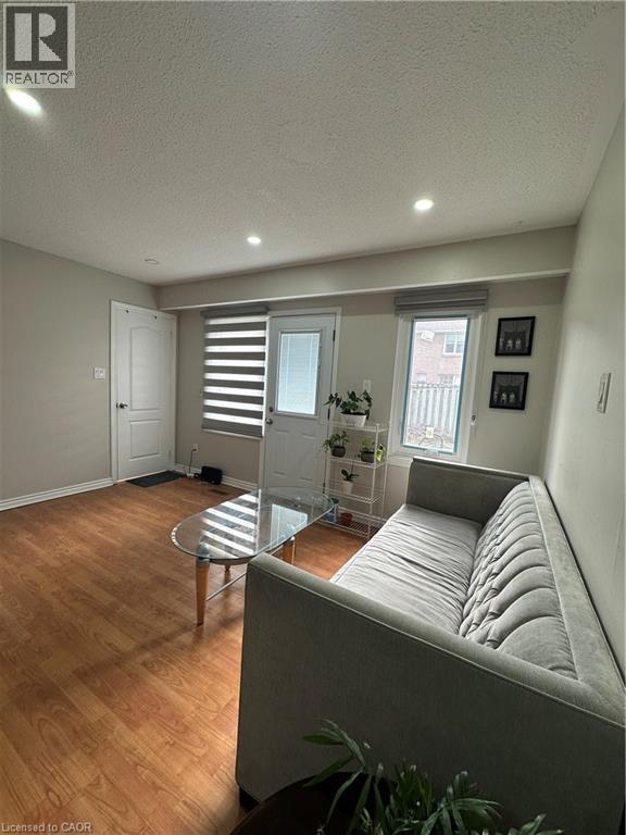 Living area featuring wood-finish flooring, recessed lighting, and a rear door with an adjacent window