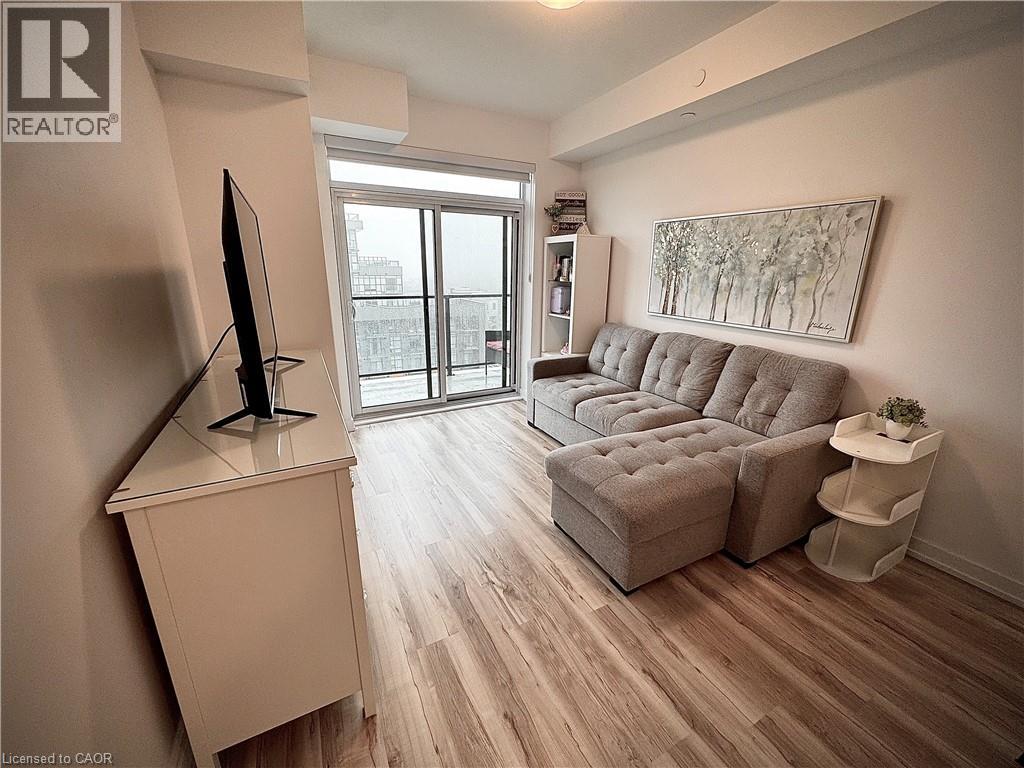 Living area featuring wood-finish flooring, a full-height sliding glass door, and an overhead lighting fixture