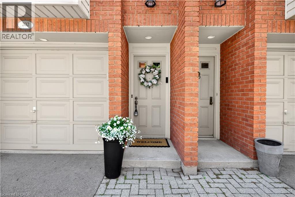 Brick facade with two paneled garage doors, individual entryways, and exterior lighting fixtures