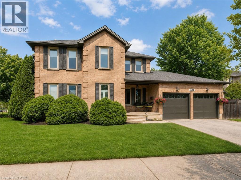 Brick-front residence with a two-car garage, mature landscaping, and a covered porch