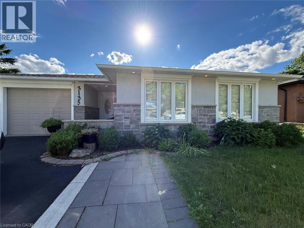 Exterior featuring a light stucco finish, stone veneer accents, multiple large windows, an attached garage, and a paver walkway
