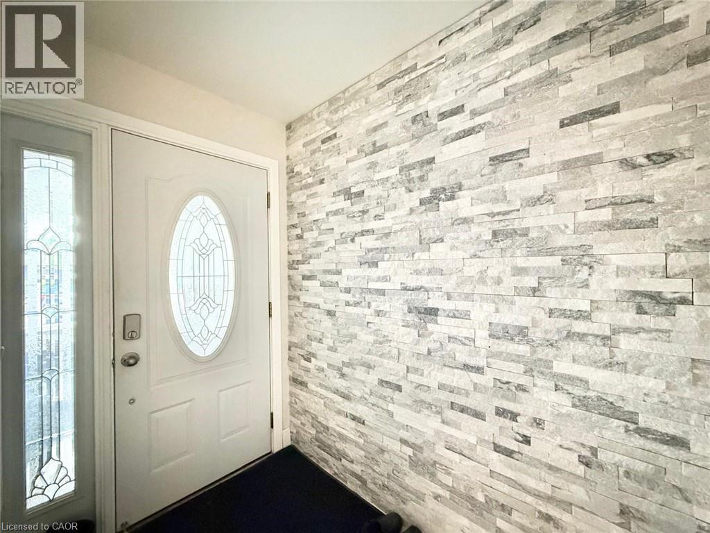 Entryway featuring a white door with decorative oval glass insert, sidelight with leaded glass, and an accent wall with stacked stone tile