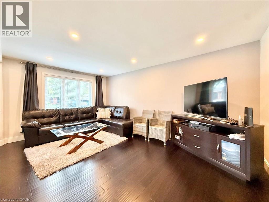 Spacious living area featuring dark wood-finish flooring, recessed lighting, and a large window with blinds
