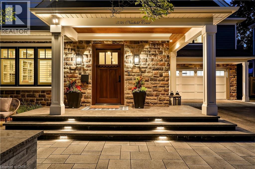Stone facade entry with a wood front door, covered porch, integrated step lighting, and an attached two-car garage