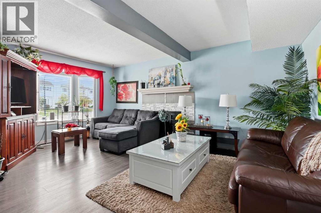 The bright living room has laminate flooring and a cozy wood-burning fireplace