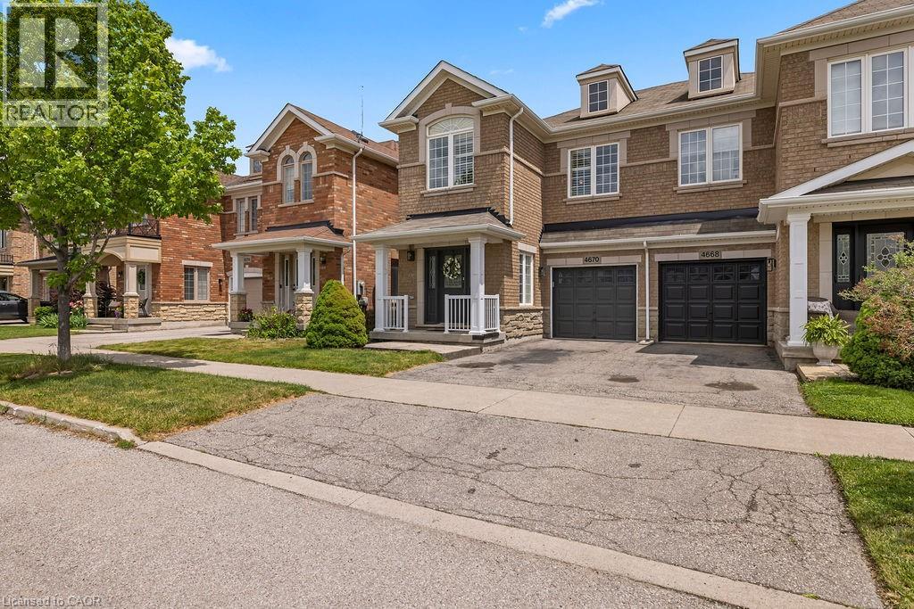Brick facade townhouse featuring a covered front porch with white railings, two attached garage doors, and dormer windows