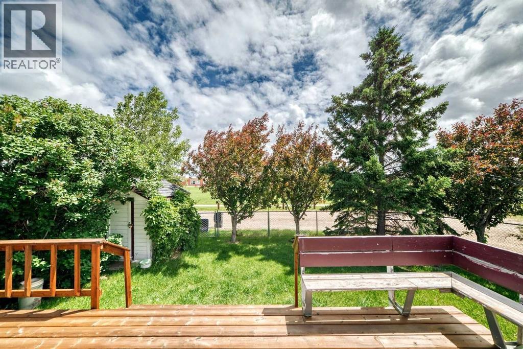 A peek outside showcases a deck with integrated seating, overlooking a fenced, mature backyard. Note the storage shed for your gardening tools. Back inside we go!