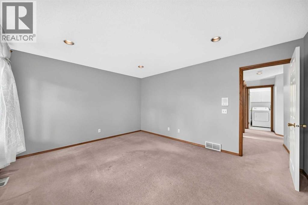 Another look at the main bedroom suite reveals a functional layout, featuring a clear view into the adjacent main-floor laundry room