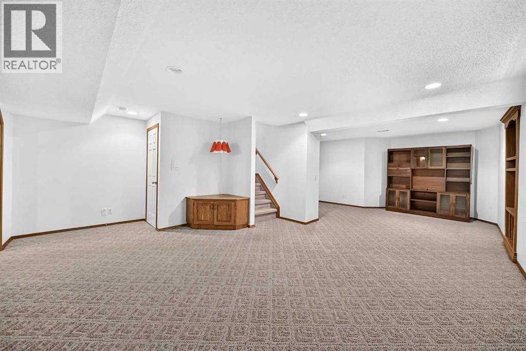 Another image of the lower-level, larger recreation/family room, showing another built-in unit and the staircase. This is a very large room