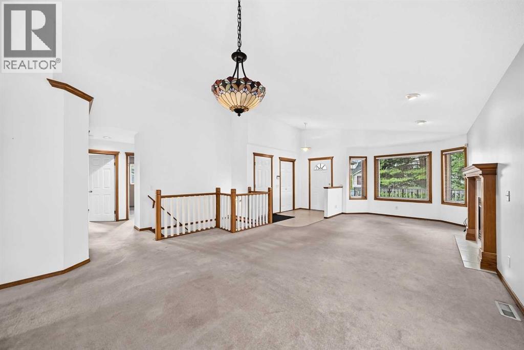 Alternate view of the foyer and living room featuring a classic Tiffany-style chandelier. The hallway to the left leads directly to the main floor laundry and sleeping quarters