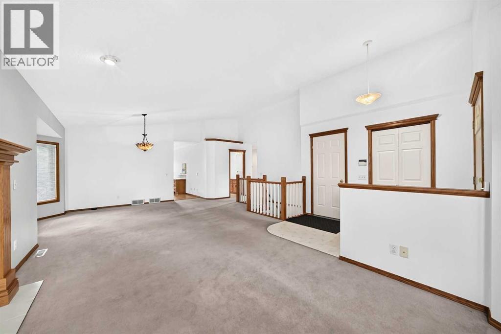 Alternate living room view highlighting the spacious vaulted ceiling. Note a built-in seasonal display ledge on the right, positioned in front of the staircase railings