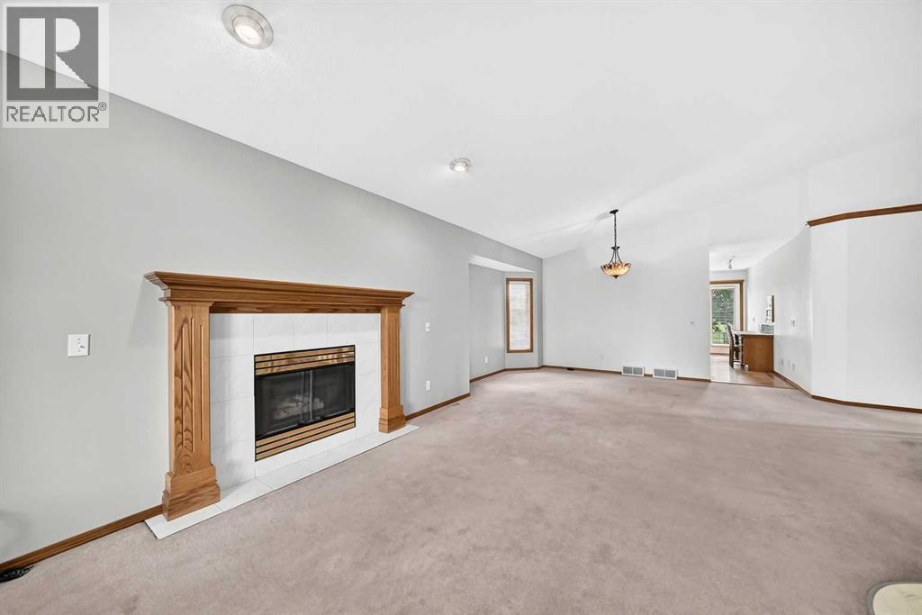 Living room immediately left of entry, featuring a gas fireplace with an oak mantle, pillars, and glass doors, with the dining room positioned just beyond