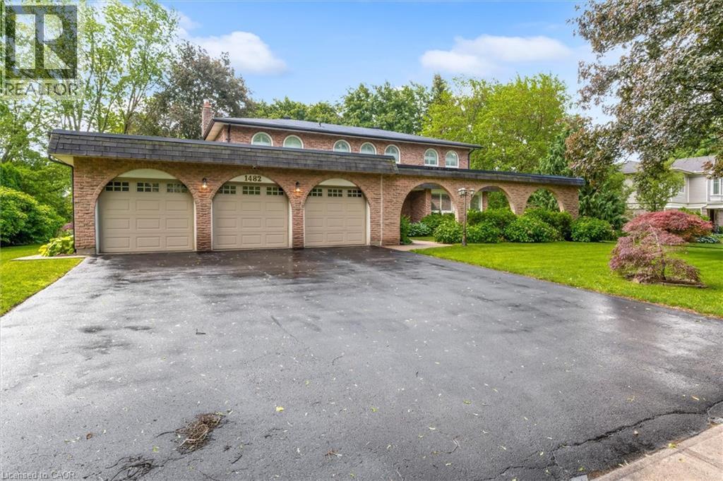 Brick façade residence featuring an arched three-car garage and a paved driveway