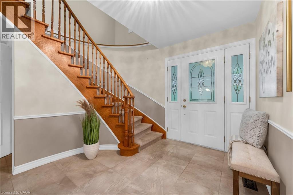 Foyer featuring a grand staircase with wood balusters, carved newel posts, and carpeted treads
