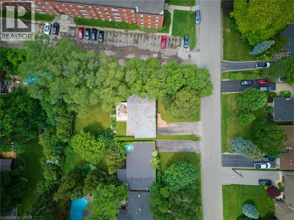Aerial perspective showcasing property with mature tree canopy, asphalt driveway, and adjacent residential street