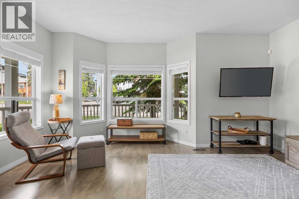 Oversized bay windows wrap this living space in light, offering leafy street views and a calm, airy atmosphere