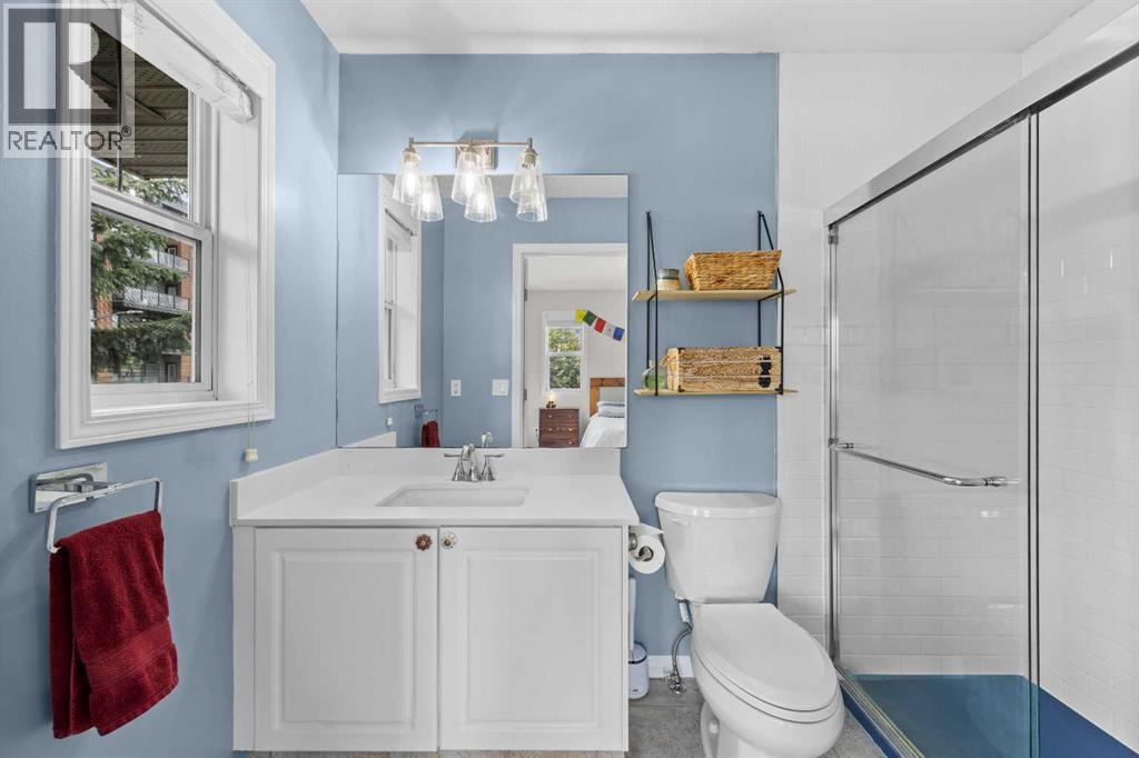 The crisp three piece ensuite features a walk in glass shower, quartz topped vanity, and a cheerful, light filled palette