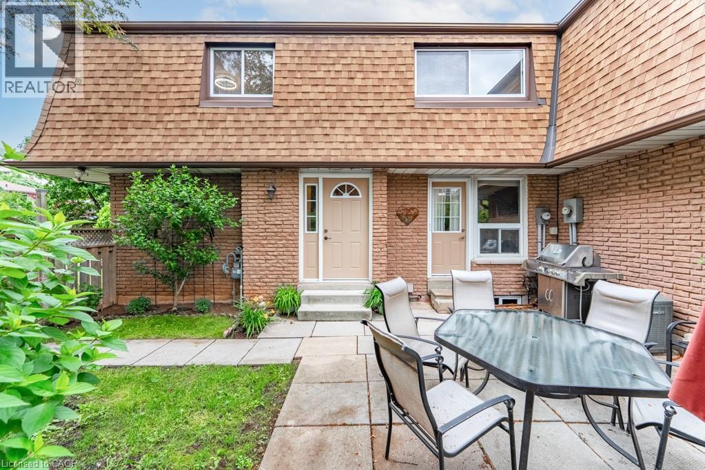 Exterior featuring a gambrel roofline, brick siding, and a stone patio