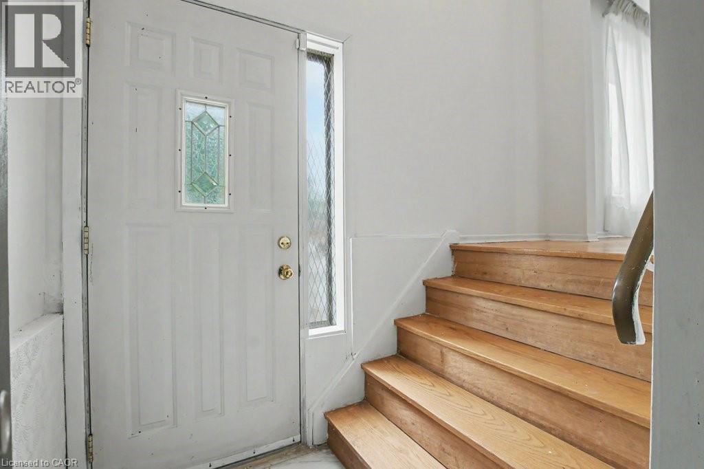 Entryway featuring a paneled door with decorative glass insert and a sidelight, alongside wood-finish stairs with a coordinating handrail