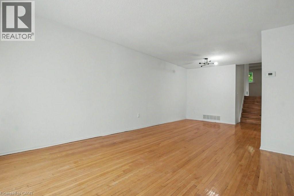Spacious room featuring wood-finish flooring and a contemporary black ceiling fixture