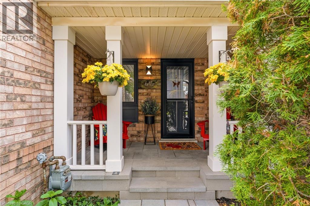 Brick exterior featuring a covered porch with white columns, a dark entry door, and stone steps