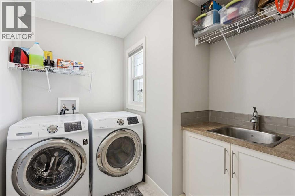 Laundry on the upper level with a utility sink and tile flooring