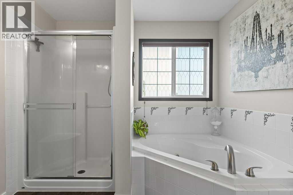 Spacious primary ensuite featuring dual sinks, a relaxing soaker tub, and separate shower