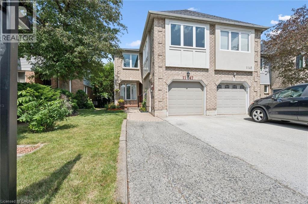 Brick facade residence featuring a two-car garage, multiple upper-level windows, and a paved driveway