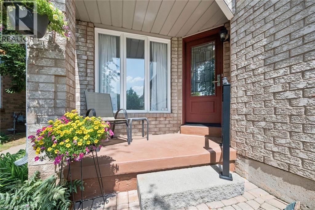 Front entry featuring a red-hued door with decorative glass, light brick exterior, and a concrete porch with steps