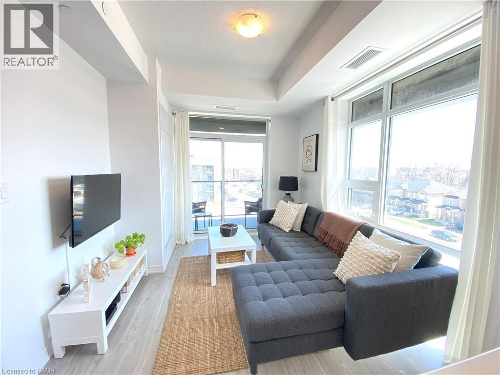 Bright living area featuring laminate flooring, a full-height window, and a sliding glass door to a balcony