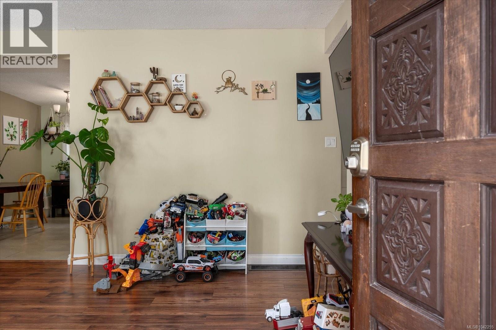 Entryway featuring a carved wood door with smart lock hardware, wood-finish flooring, and light-toned wall paint